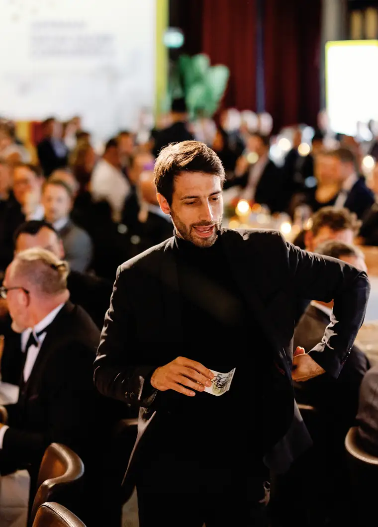 Zauberer Oliver Henke geht mit Spielkarten in der Hand durch ein Firmen-Galadinner